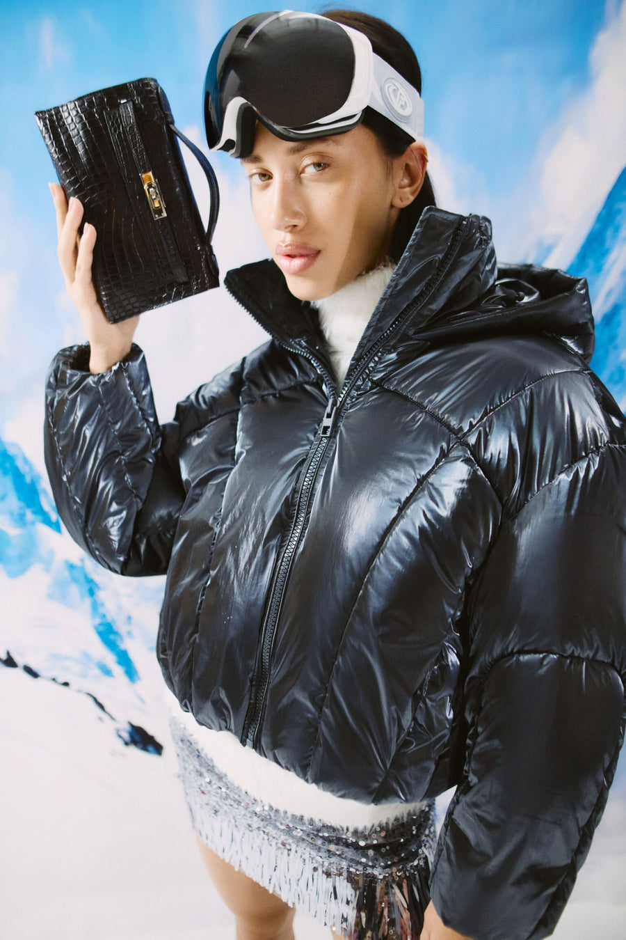 Hermès Kelly Pochette Black Alligator Gold Hardware, held beside the face by a model