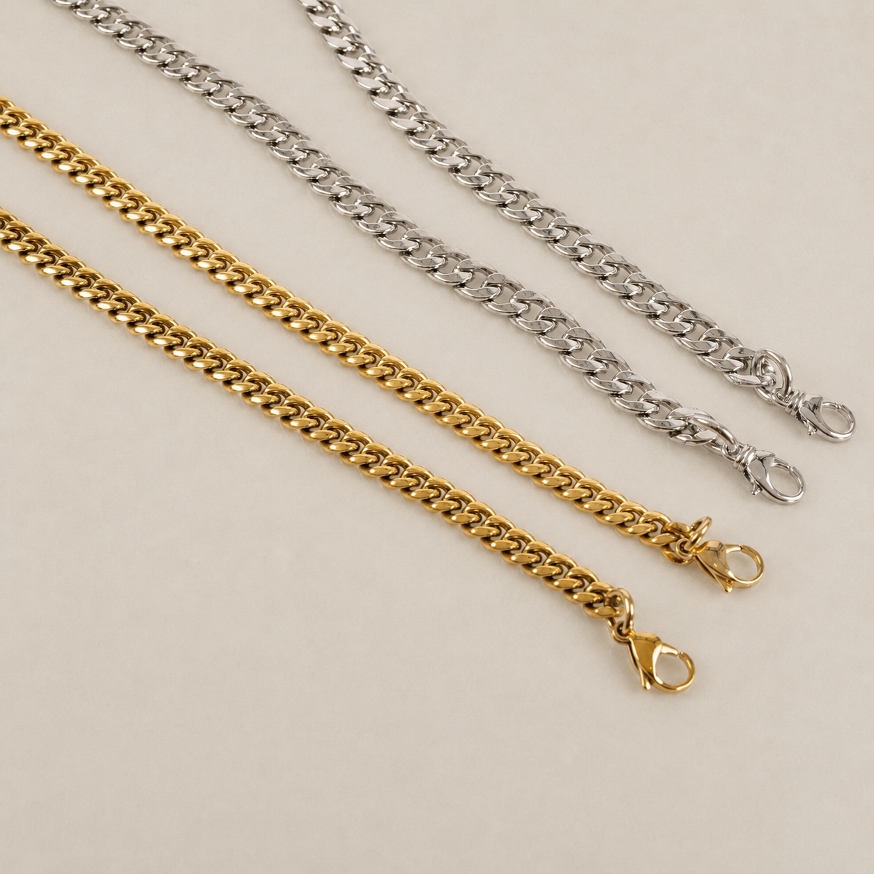JaneFinds Cuban crossbody chains in gold and palladium finishes on a warm neutral studio background
