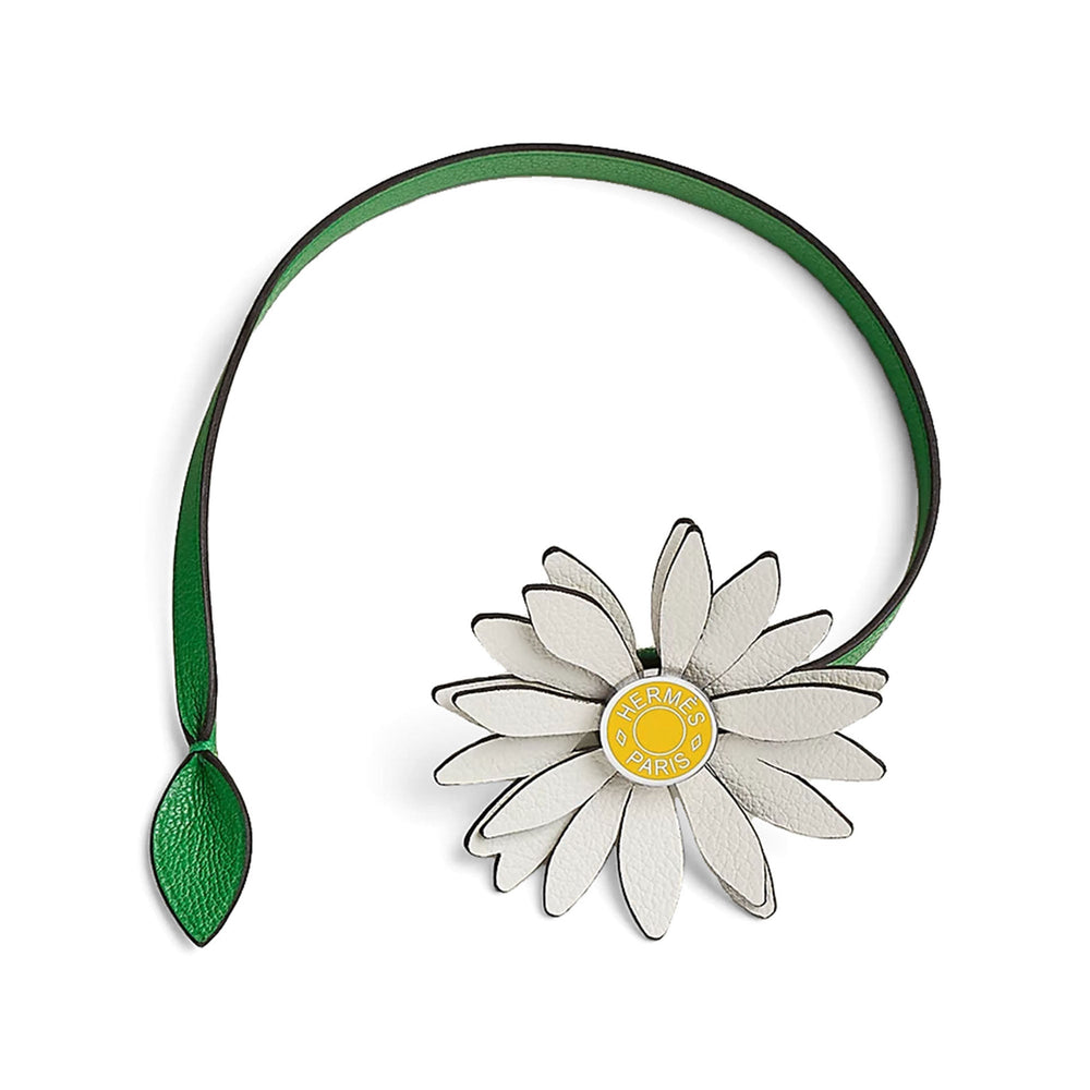 Hermès Marguerite Daisy Charm in White, Jaune de Naples and Bambou, looped green leather strap and leaf on white with a soft natural shadow.
