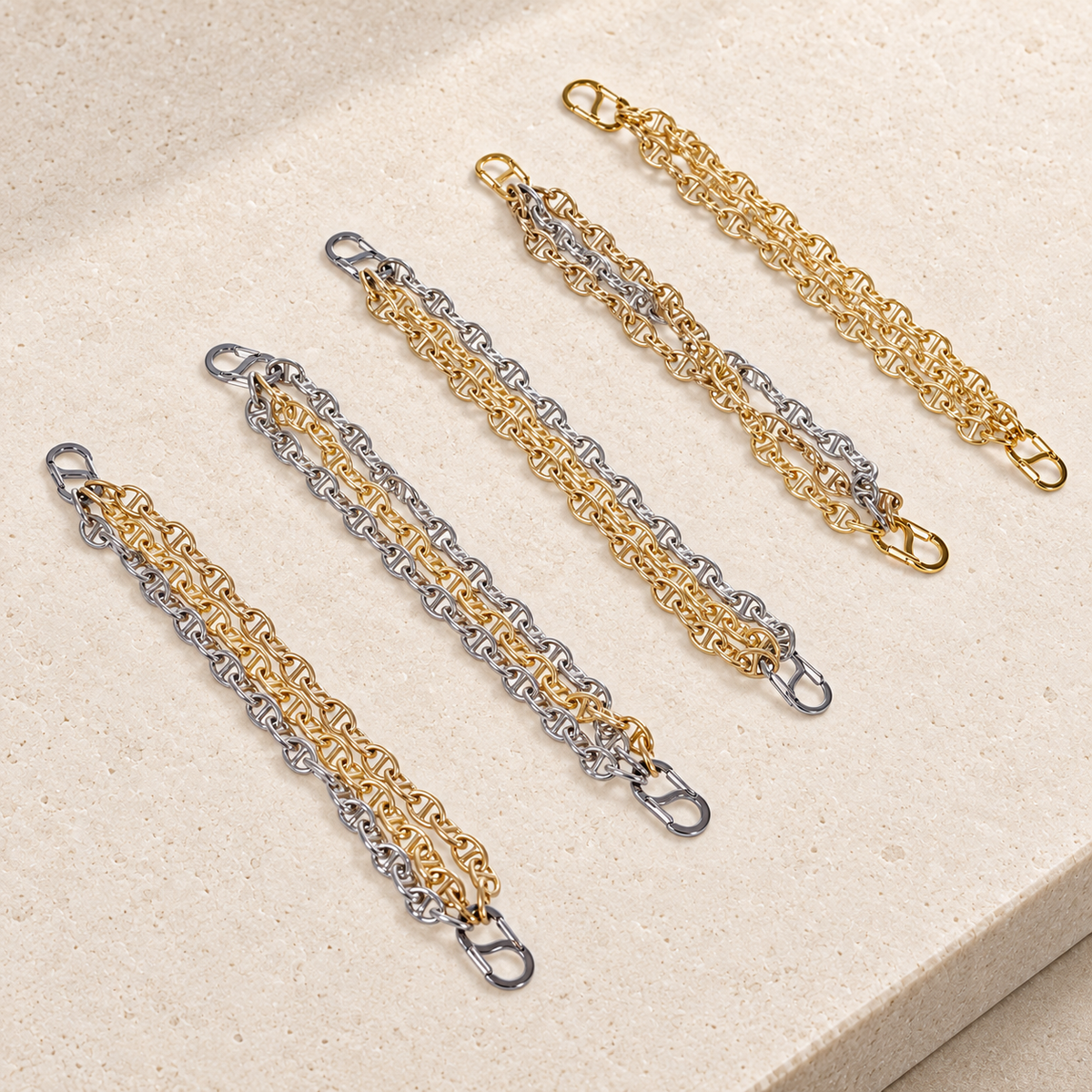 JaneFinds Convertible Triple Mariner extenders with gold and palladium strands and double-opening clasps on pale limestone.
