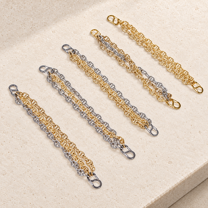 JaneFinds Convertible Triple Mariner extenders with gold and palladium strands and double-opening clasps on pale limestone.