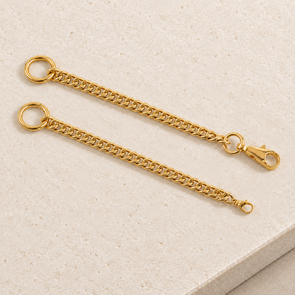 JaneFinds gold Cuban extender chains with large circular rings and two clasp sizes on pale limestone.