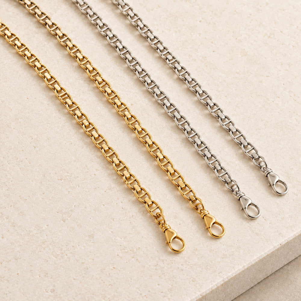 JaneFinds Full Mariner crossbody chains in Gold and Palladium with continuous anchor links and rounded clasps on pale limestone.