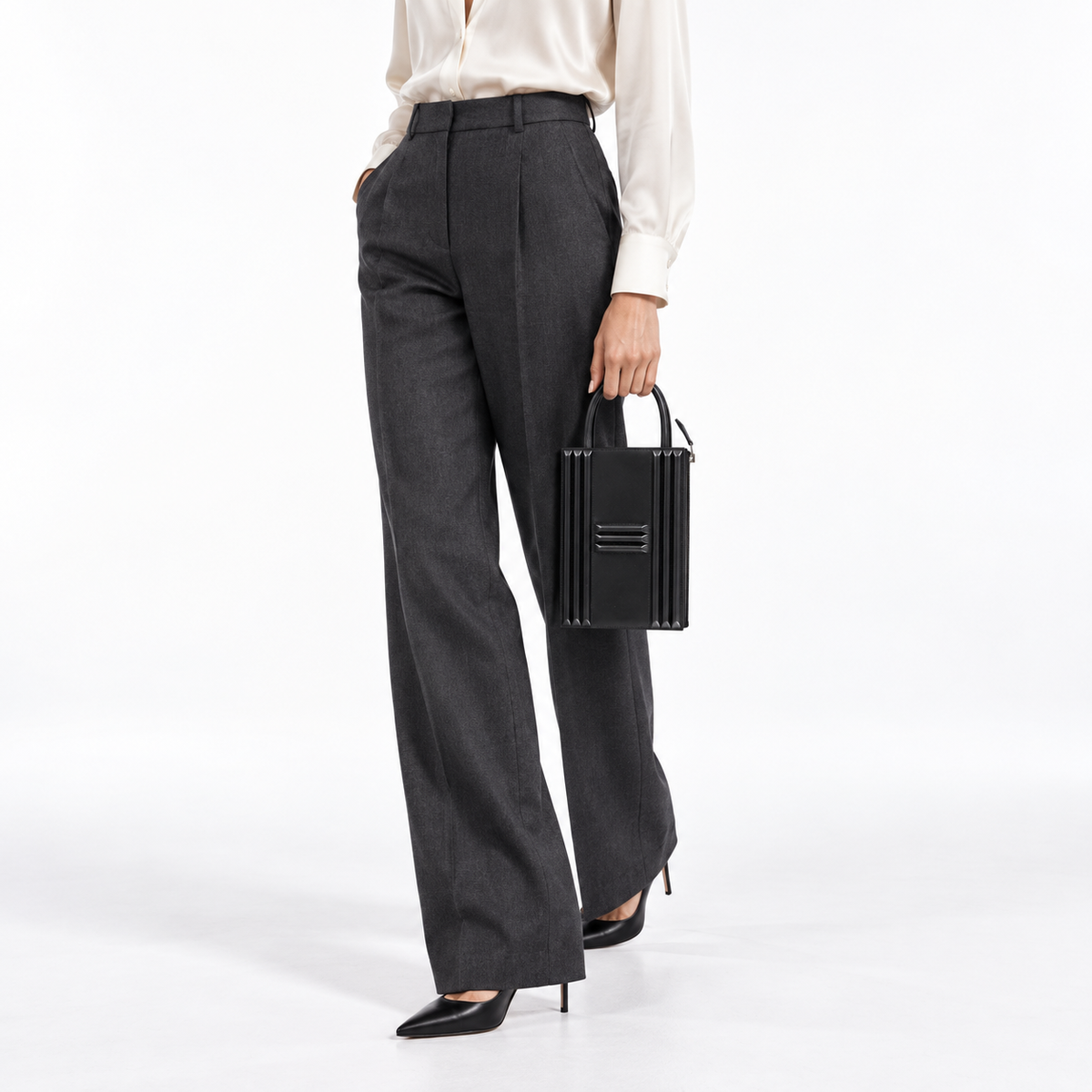Hermès Cadena Lock Bag in black Tadelakt with palladium hardware, angled hand-carry studio view on a model