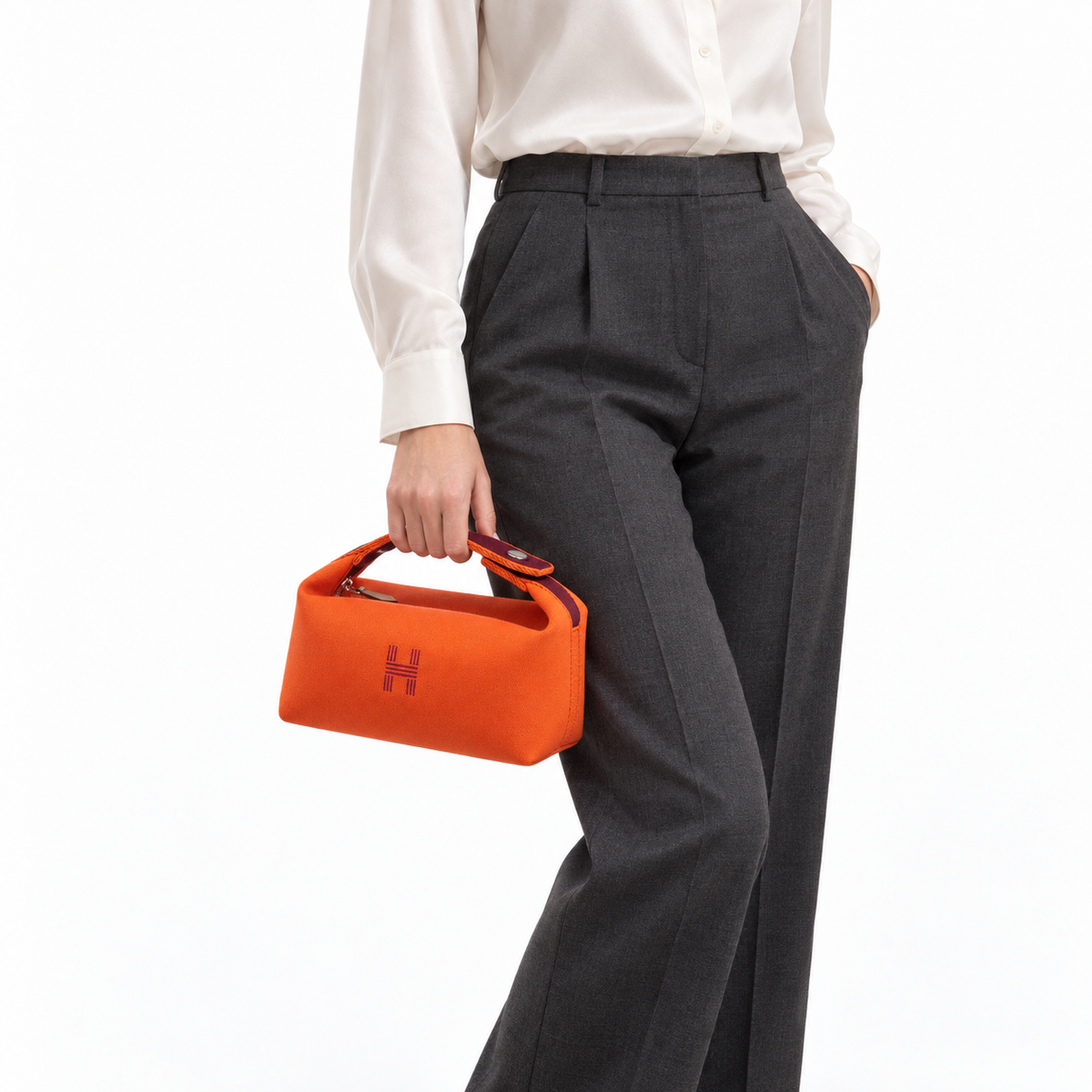 Hermès small Bride-a-Brac pouch in orange canvas with burgundy handle and embroidered H, angled hand-carry studio model view