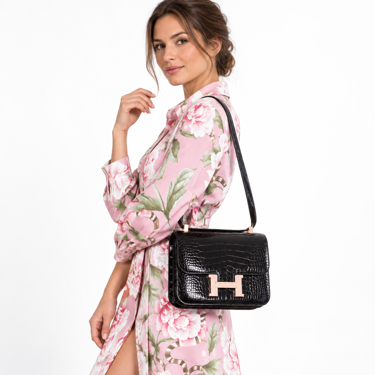 Hermès Constance 24 black alligator with rose gold hardware worn by a model in a pink floral dress against a white studio background