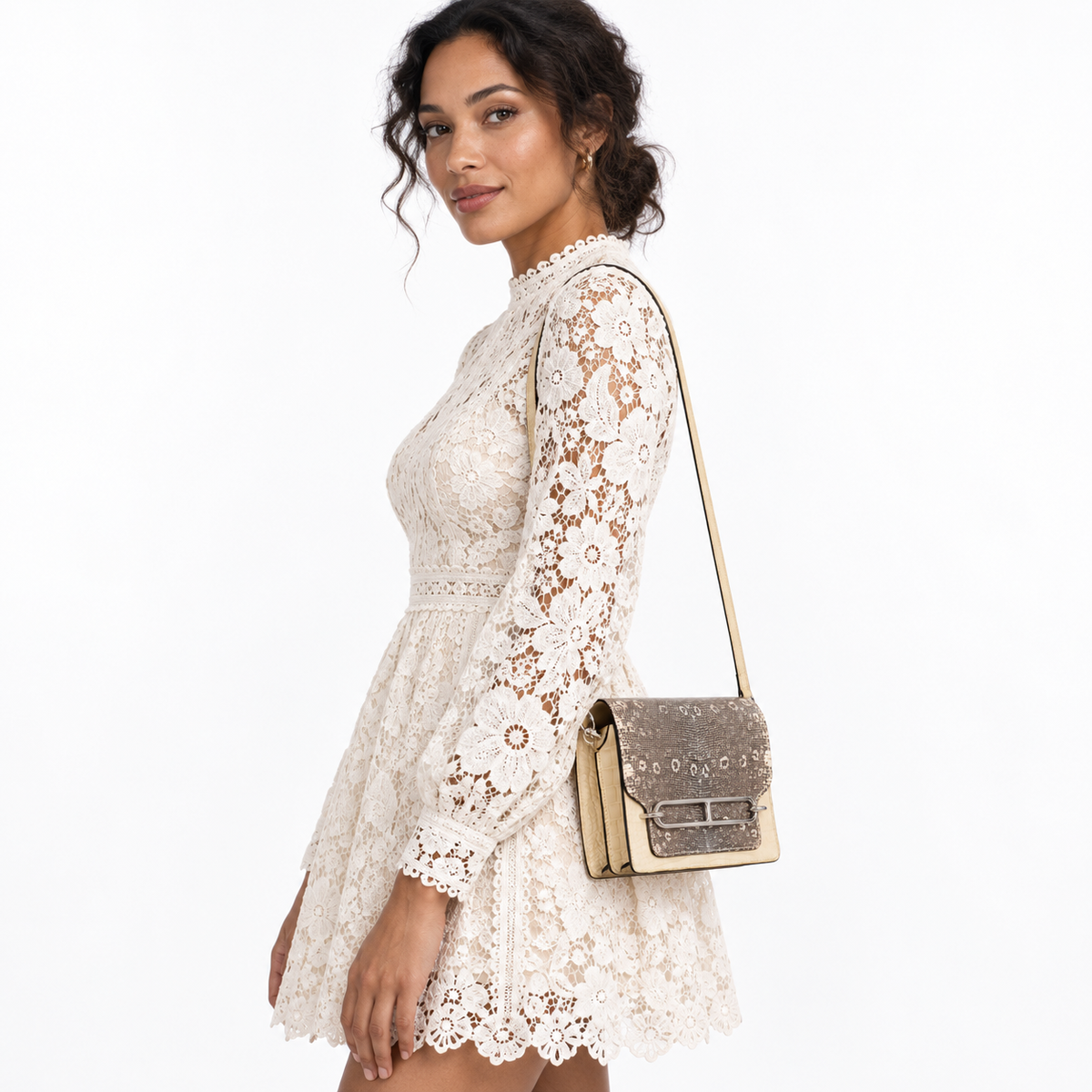 Hermès Roulis Mini Ombré Vanille alligator and Natura lizard bag with palladium hardware worn by a model in an ivory lace dress on a white studio background