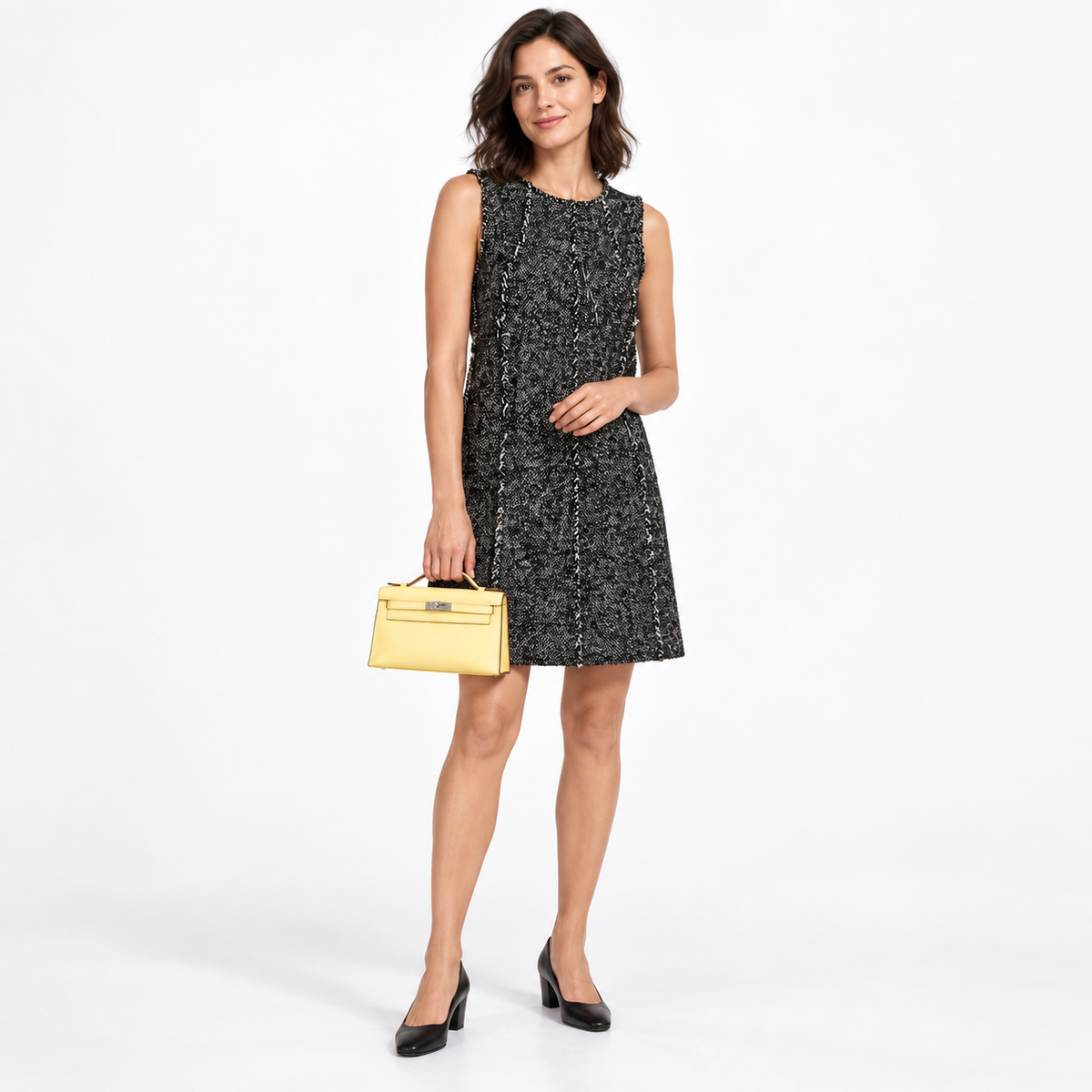 Hermès Kelly Mini Pochette Jaune Poussin Swift Palladium Hardware carried by a model in a white studio