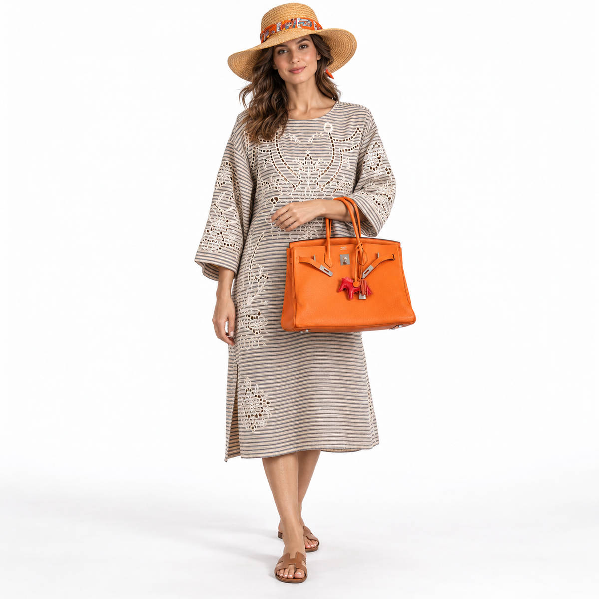 Hermès Birkin 35 Orange Clemence Palladium Hardware with Rodeo charm, carried by a model in a white studio