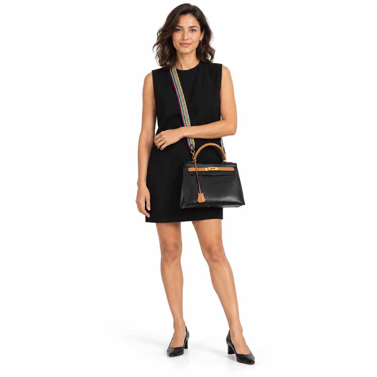 Hermès Kelly 28 Black Ardennes and Barenia with gold hardware worn crossbody by a woman in a black dress in a white studio