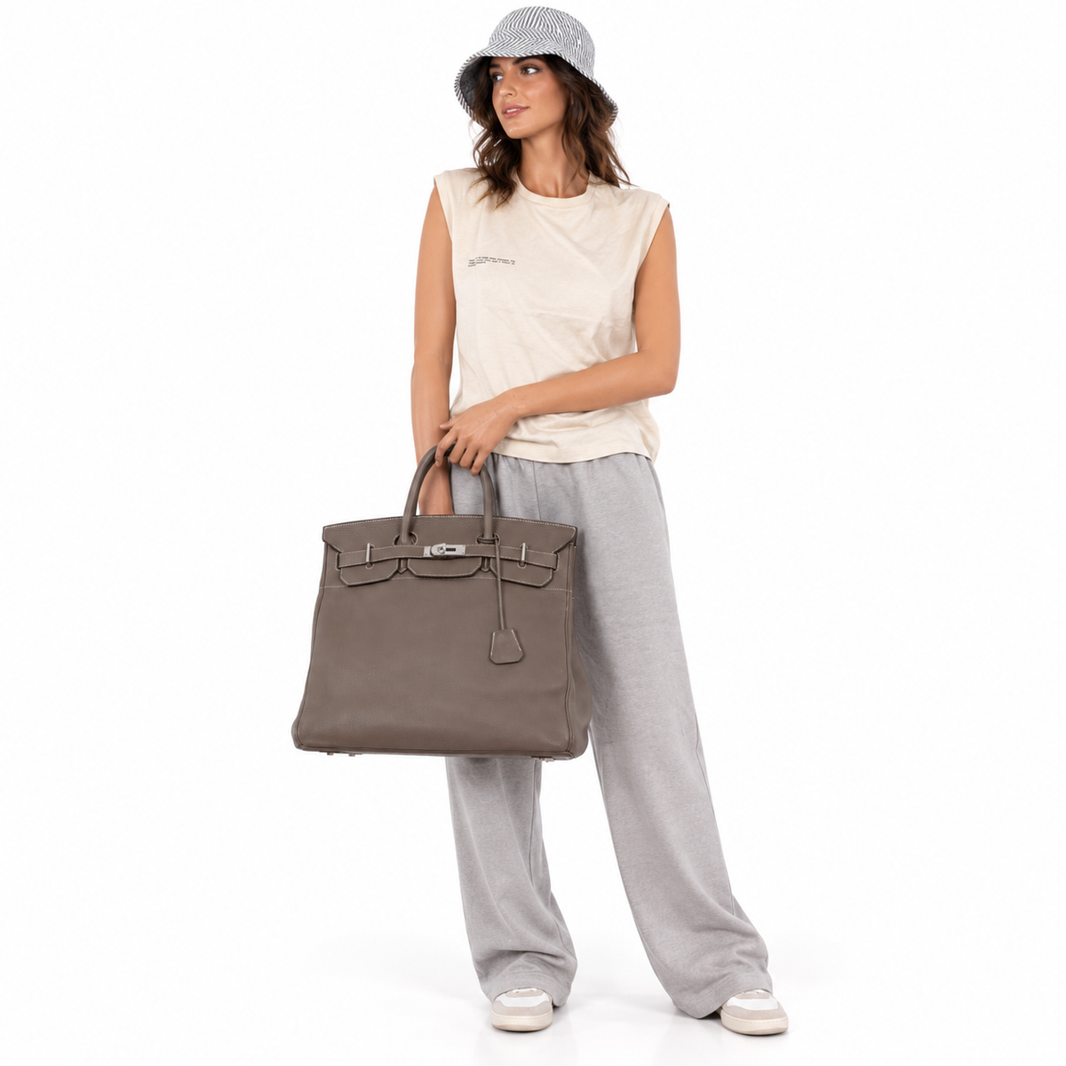 Hermès Birkin 40 HAC Etoupe Clemence Palladium Hardware worn by an adult model in a white studio