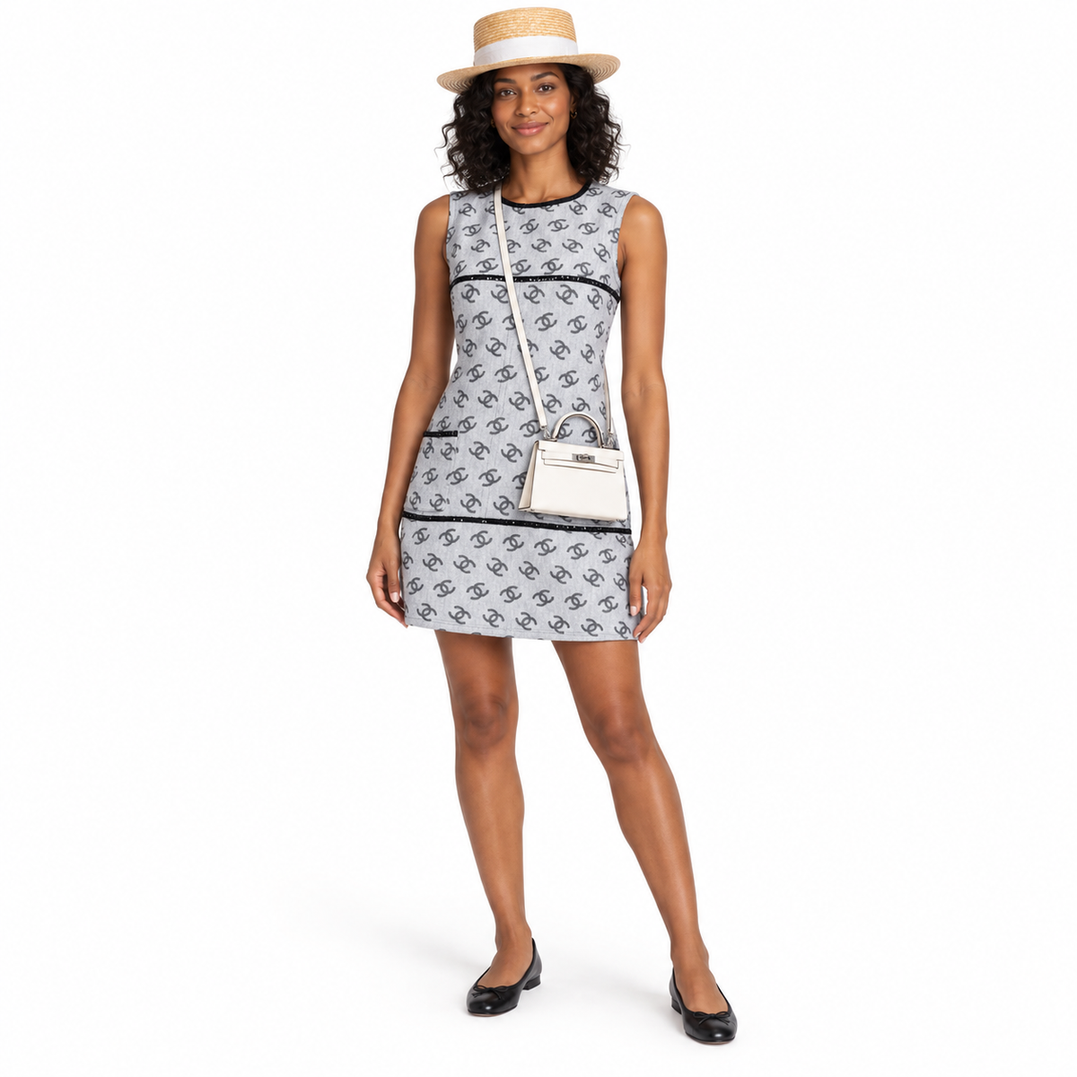 Hermès Mini Kelly 20 Nata Epsom with palladium hardware worn with its leather strap by a woman in a gray dress and straw hat