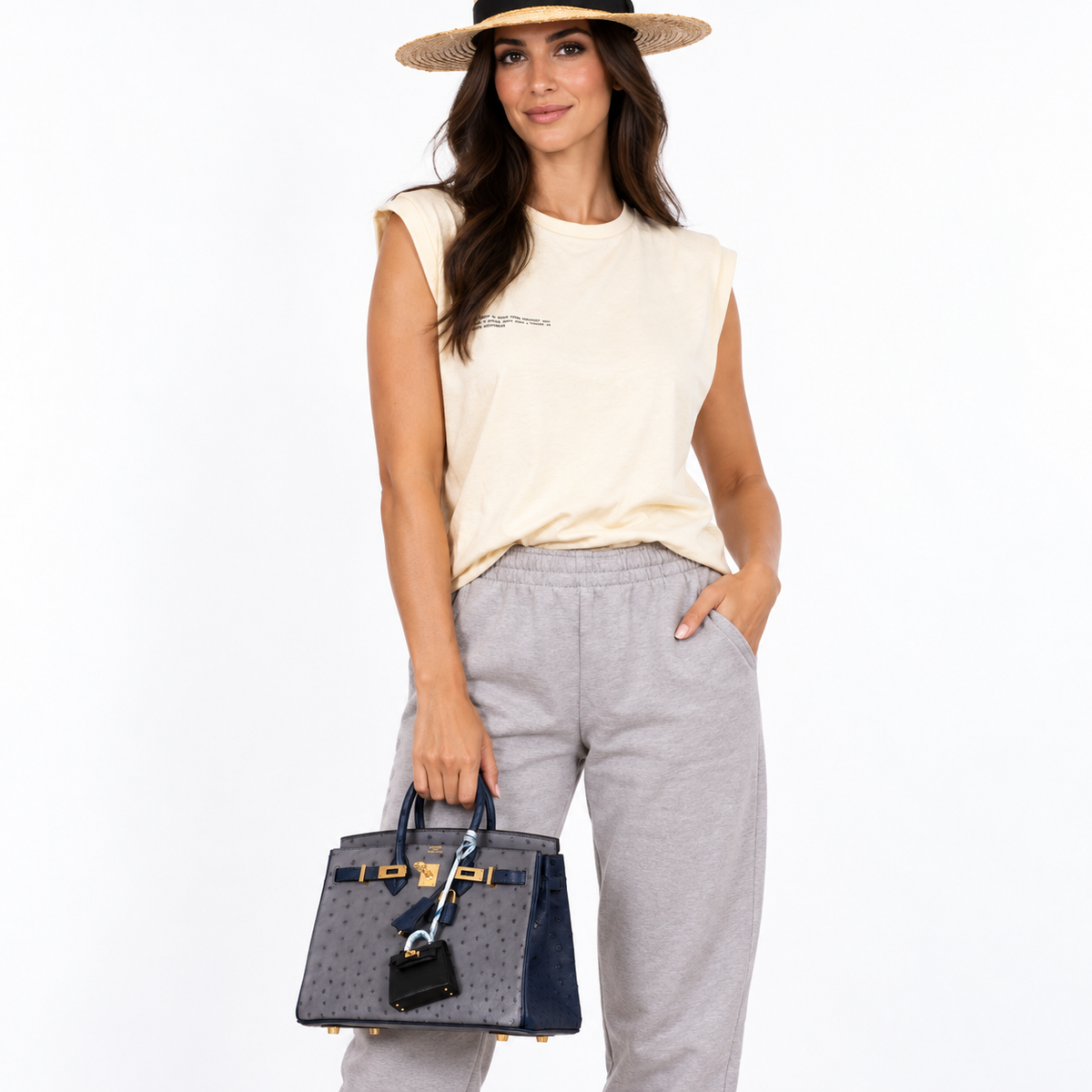 Hermès Birkin 25 HSS Gris Agate and Blue Iris Ostrich with gold hardware carried by an adult model in a white studio