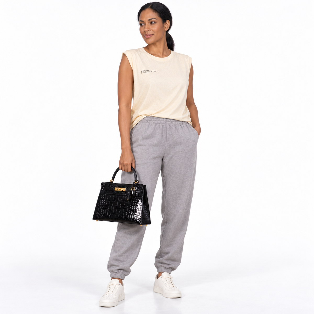 Hermès Kelly 28 black shiny alligator with gold hardware carried by a human model in a white studio