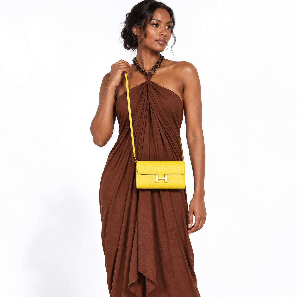 Hermès Constance Long To Go citron ostrich gold hardware worn by a model on white