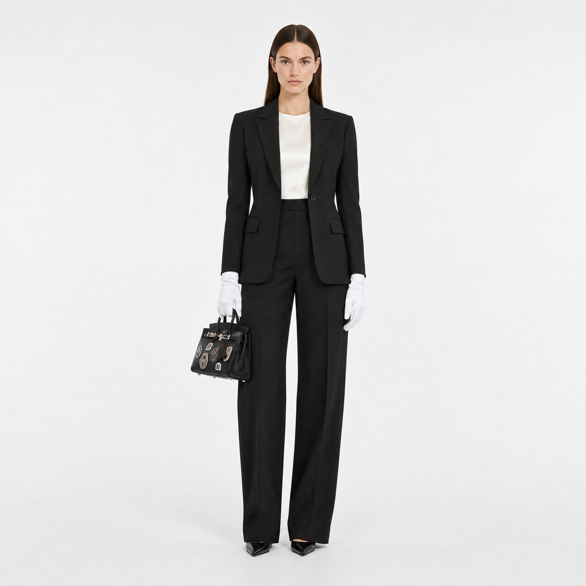 Hermès Birkin 20 Bouclerie Moderne Casaque Noir with palladium hardware, carried by a model in tailored black suiting, front view.
