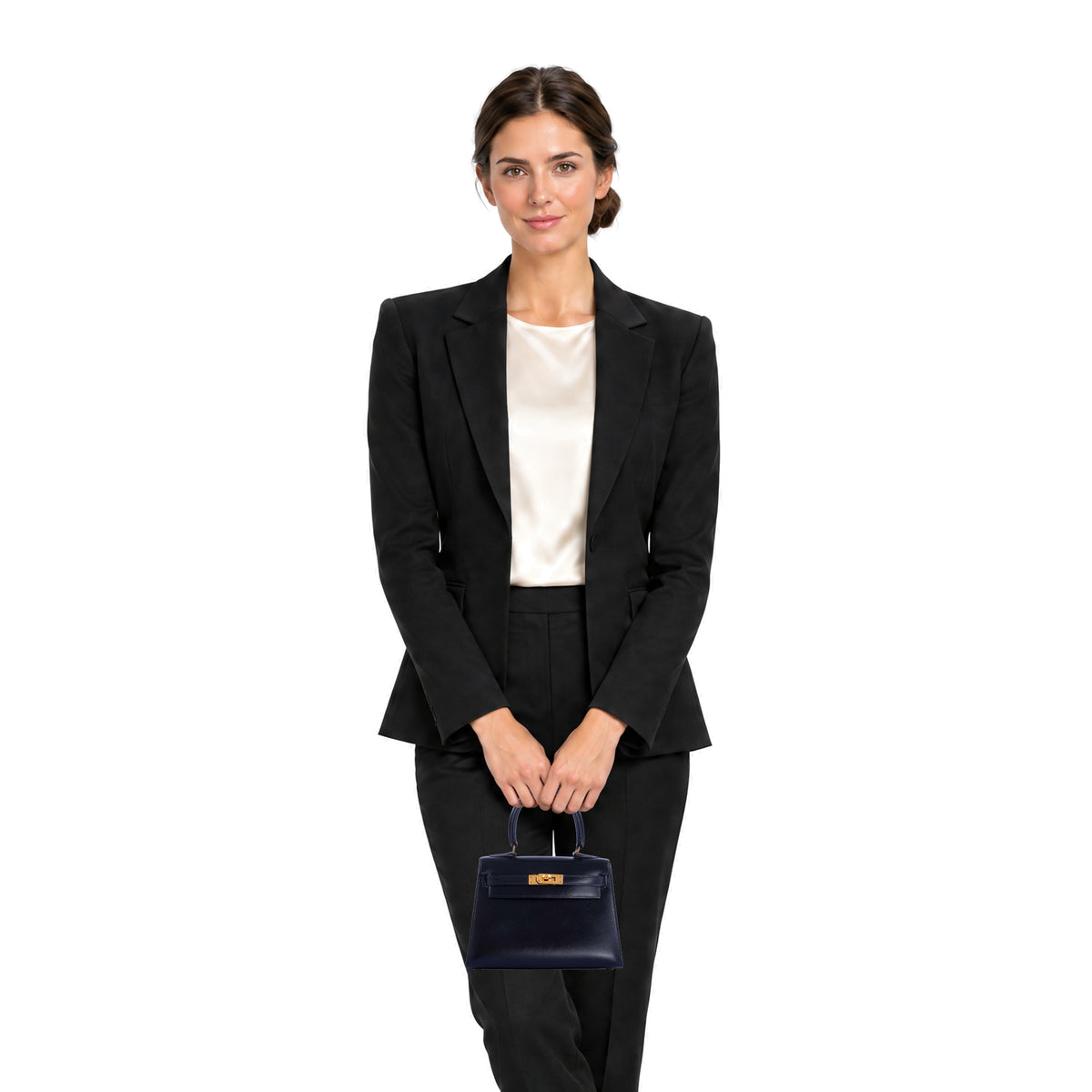 Hermès Vintage Kelly 20 Sellier Noir Box Calf Gold Hardware, held by both hands in front of the body in a relaxed standing pose.