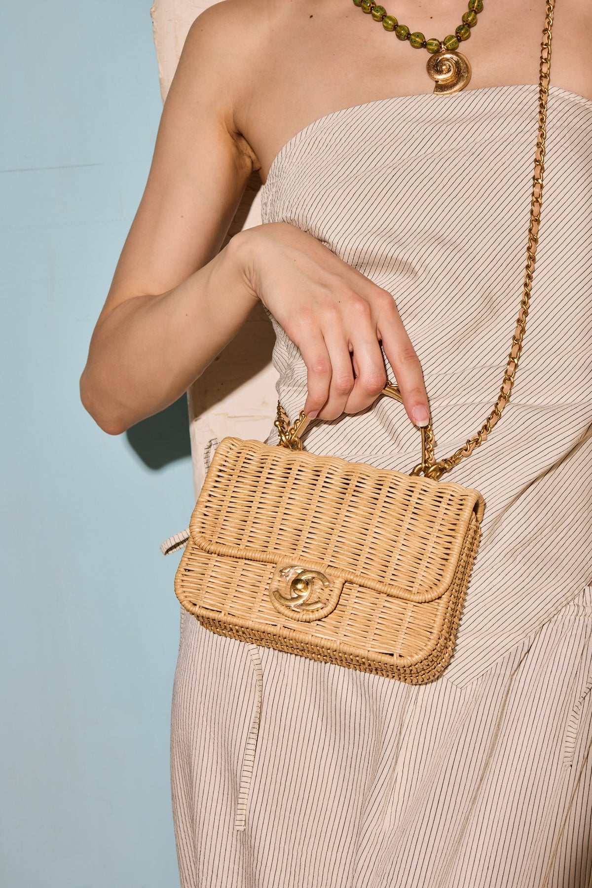 Chanel Mini Flap Bag with Top Handle Beige Braided Rattan Gold-Tone Hardware, held by the top handle by a model, close view