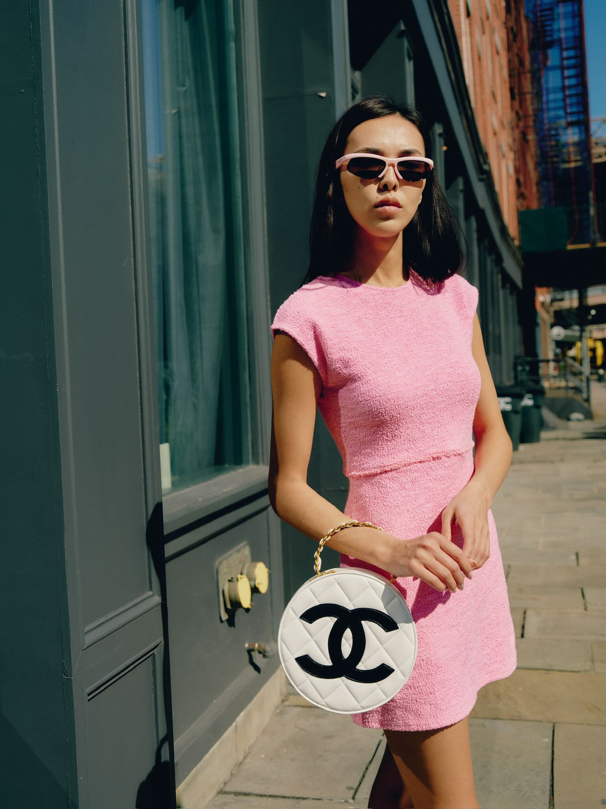 Chanel Round CC Vanity White and Black Patent Leather Gold Hardware, held by a model against a shopfront
