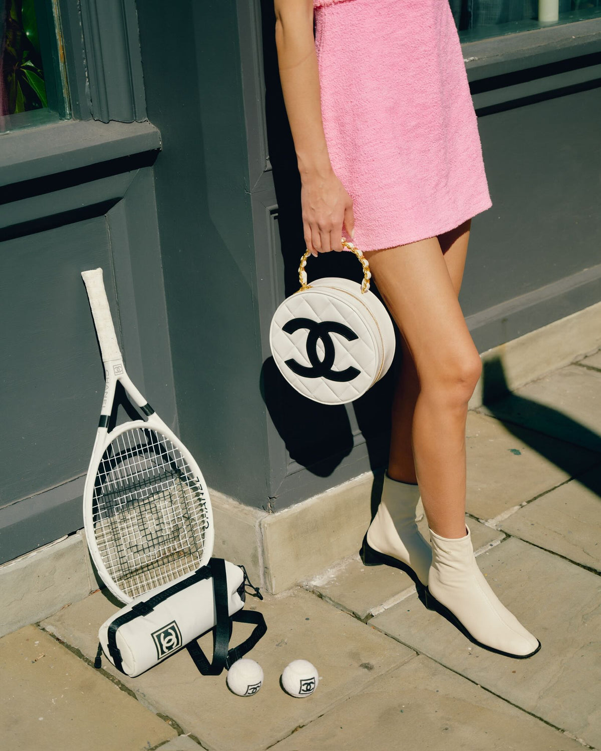 Chanel Round CC Vanity White and Black Patent Leather Gold Hardware, held by a model beside tennis gear