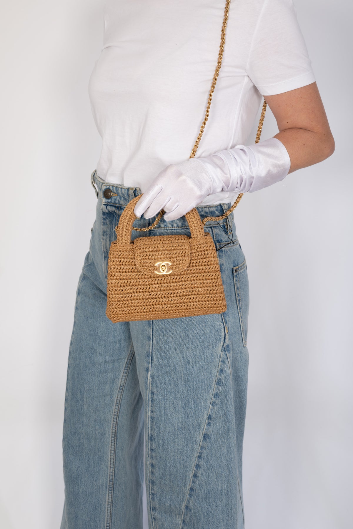Chanel Small Shopping Bag Dark Beige Braided Raffia Gold Hardware, held by a model at the top handle