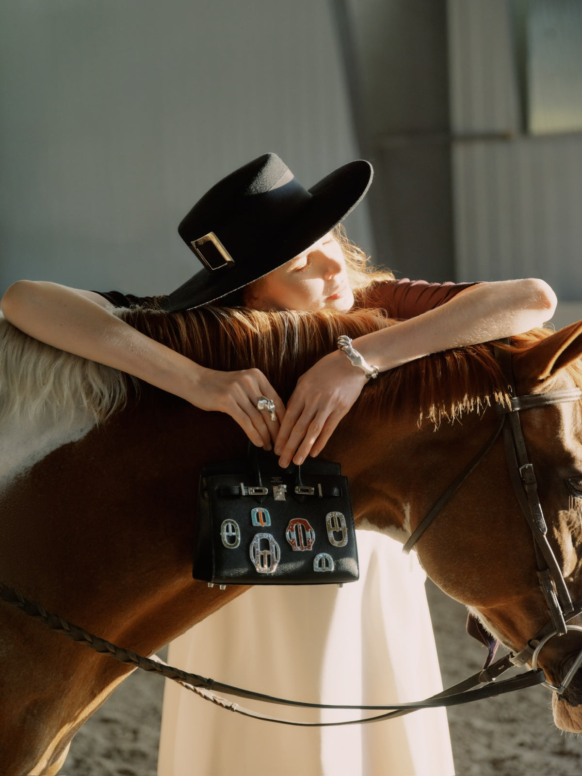 Hermès Birkin 20 Sellier Bouclerie Moderne Casaque Noir Chèvre Chamkila Palladium Hardware, held by a model leaning on a horse