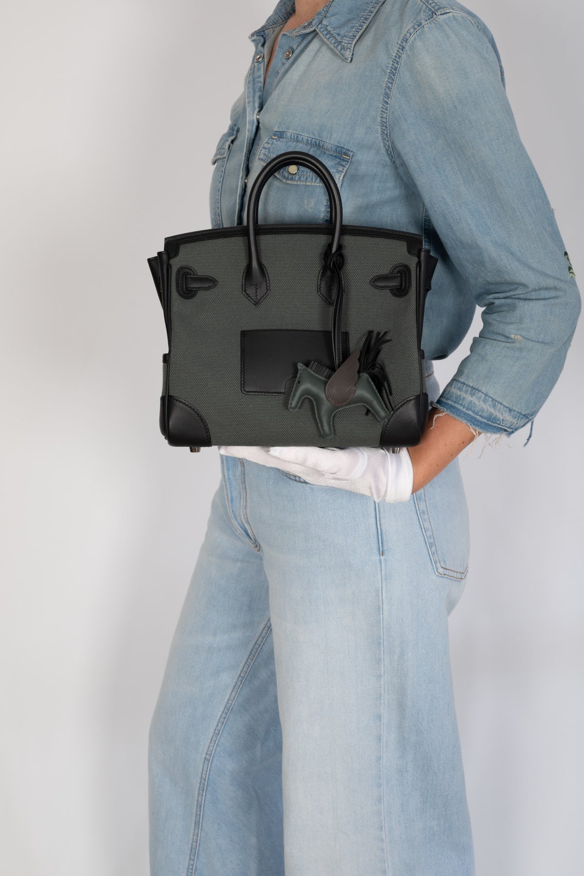 Hermès Birkin 25 Cargo Vert Mangrove Toile Goéland and Noir Swift Palladium Hardware, back view held by a model, styled with a Rodeo Pegasus charm, sold separately