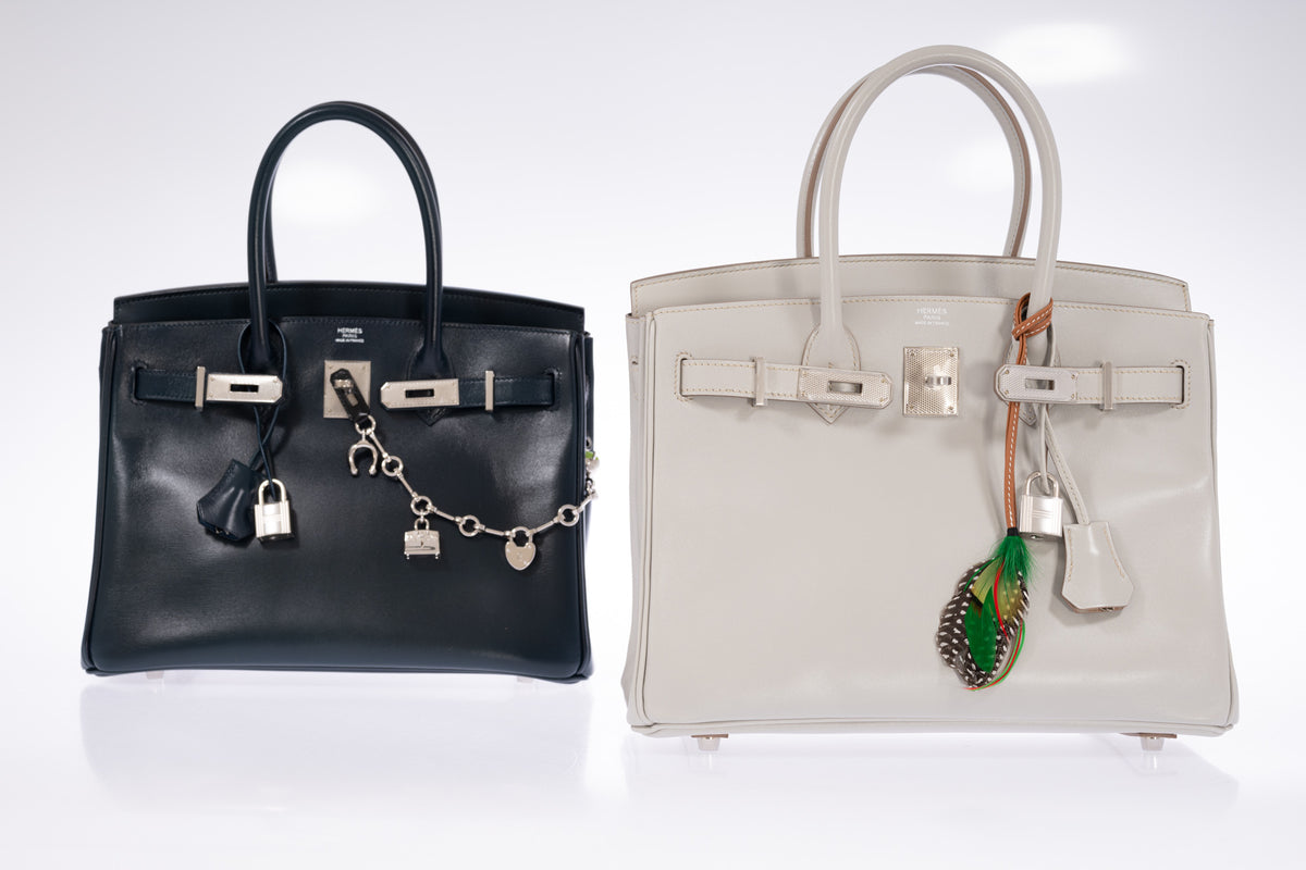 Hermès Birkin 30 Bleu de Prusse Box Calf Guilloche Palladium Hardware, shown at left with a charm chain beside a Birkin 30 Gris Perle with a feather charm, all sold separately