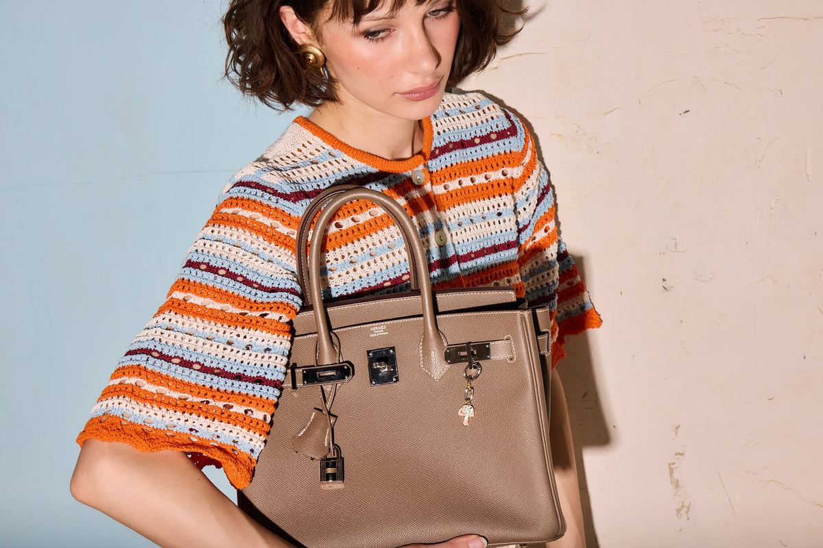 Hermès Birkin 30 Étoupe Epsom Palladium Hardware, held by a model, close view, with a charm