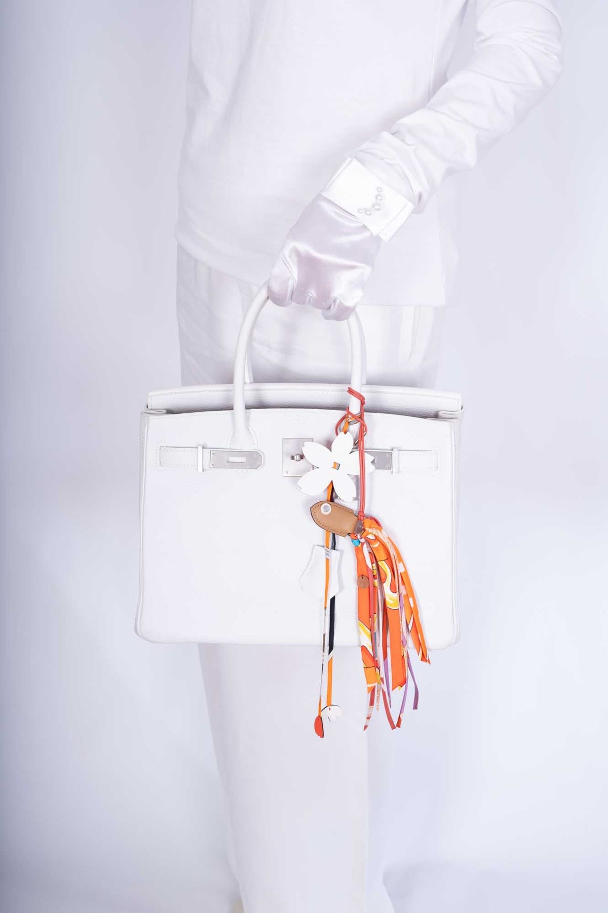 Hermès Birkin 30 HSS Blanc Clémence Brushed Palladium Hardware, held by its handles by a model, shown with charms and a twilly that are not included
