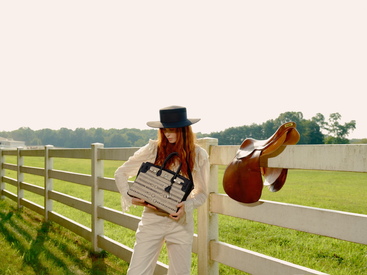 Hermès Birkin 35 De Camp Déchaînée Toile and Black Veau Swift Palladium Hardware, held at the waist by a model leaning on a fence
