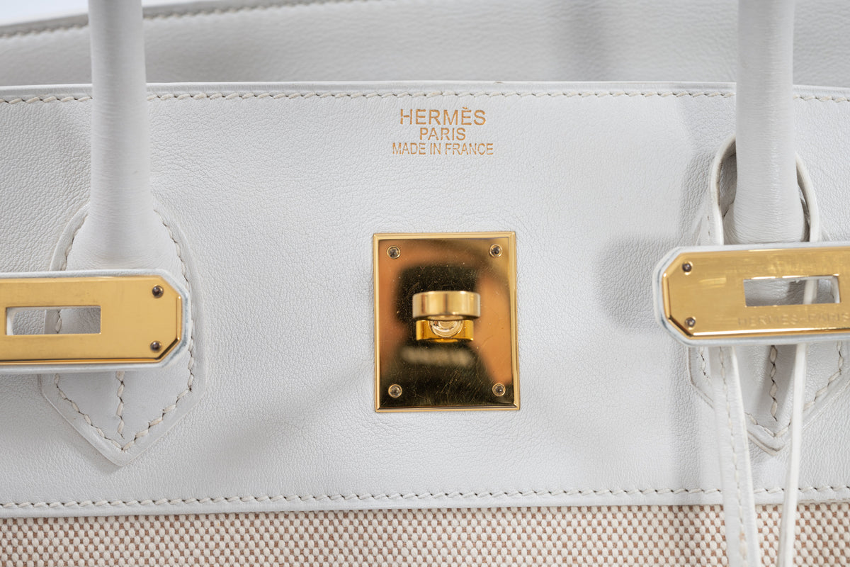 Hermès Birkin 40 Toile and Blanc Swift Gold Hardware, close-up of the HERMÈS PARIS MADE IN FRANCE heat stamp, turn-lock and strap plates, showing surface marks on the gold hardware