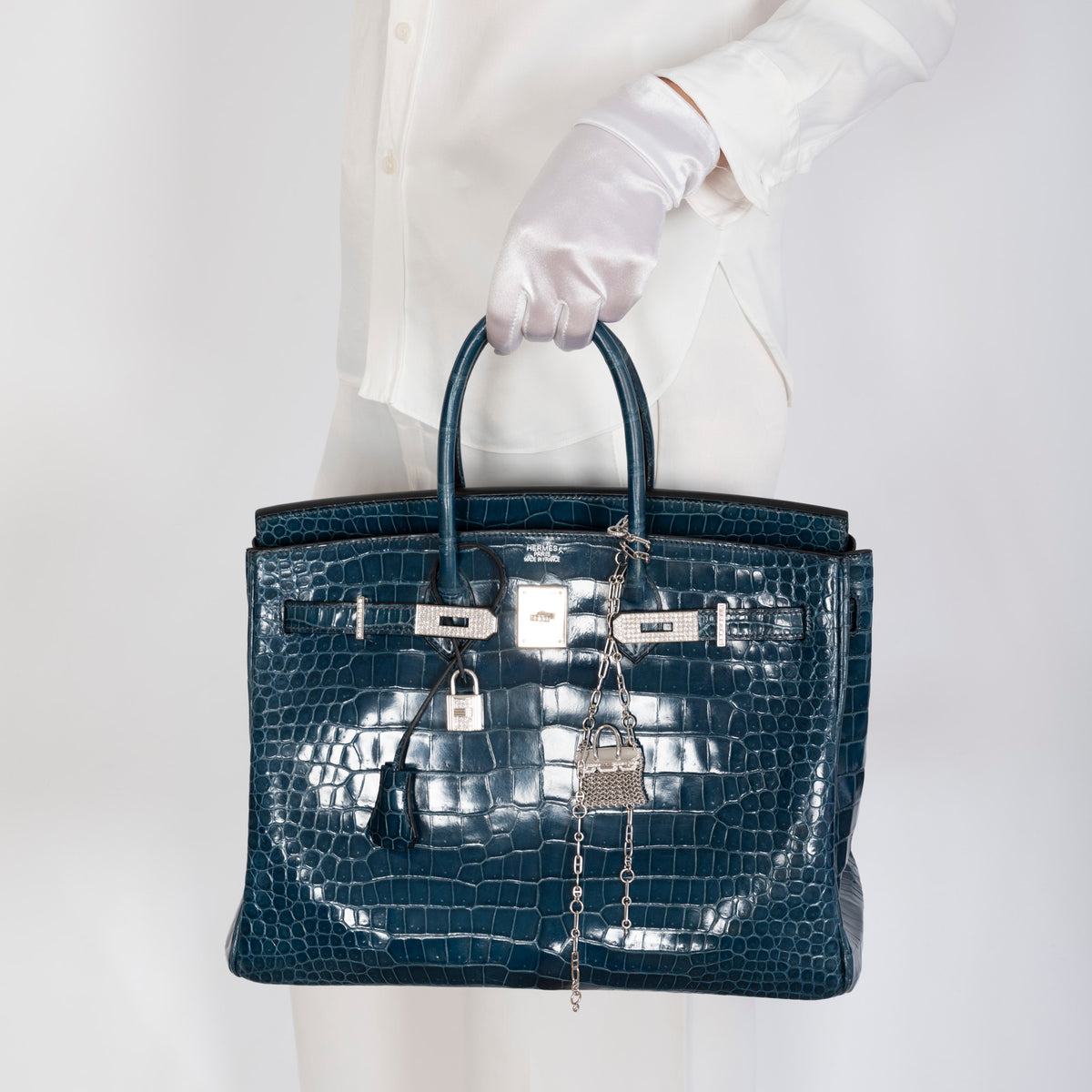 Hermès Birkin Bijou Précieux 18K White Gold Diamond Chain Mail Necklace, clipped as a bag charm to a crocodile Birkin carried by a model, bag sold separately
