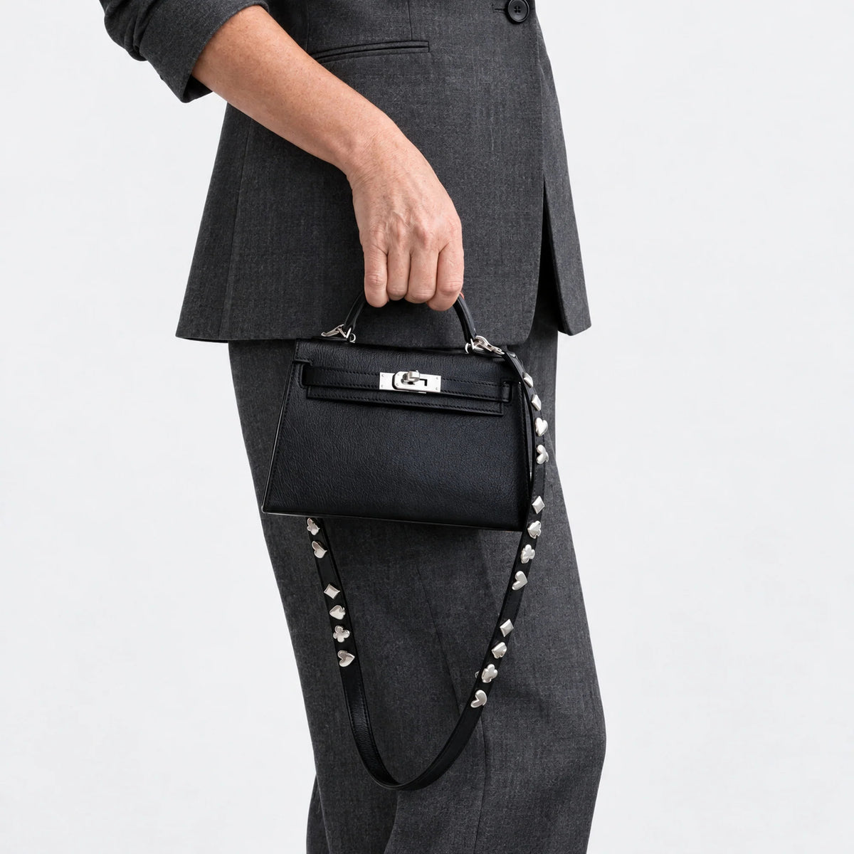 Hermès Clou de Coeur Kelly 20 Mini II Sellier Noir Chèvre Chamkila Palladium Hardware, carried by the top handle with the studded strap