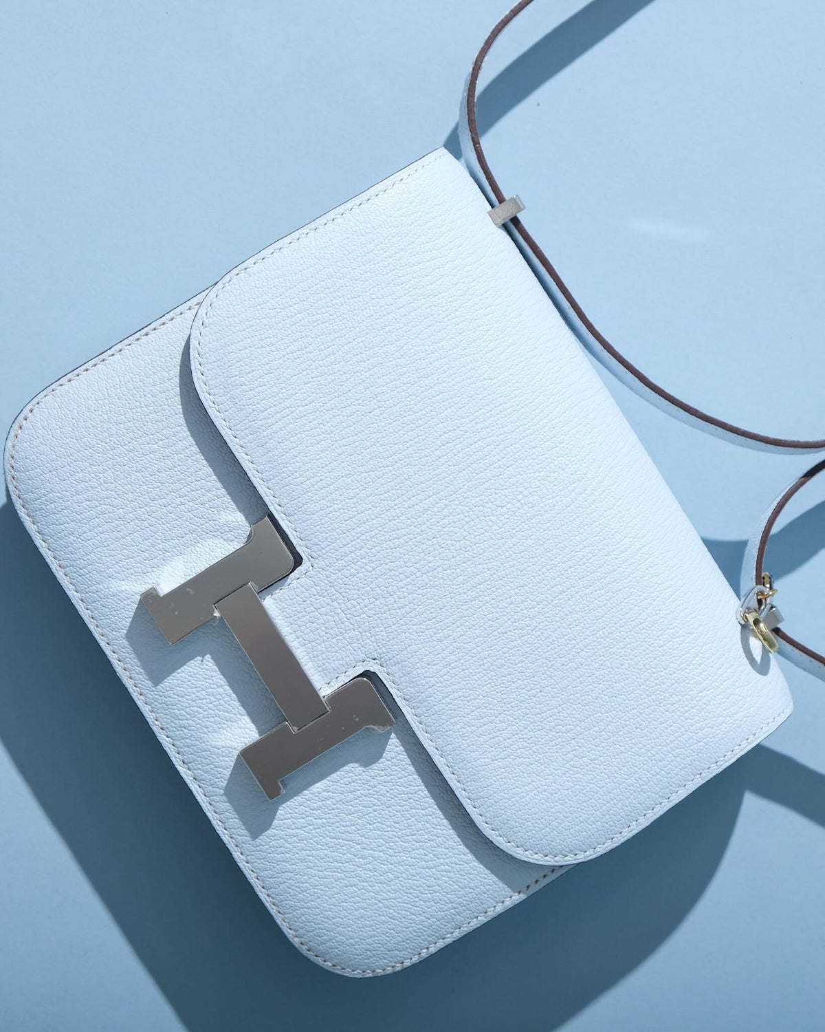 Hermès Constance 18 Blue Brume Chèvre Palladium Hardware, flat lay close view of the H clasp