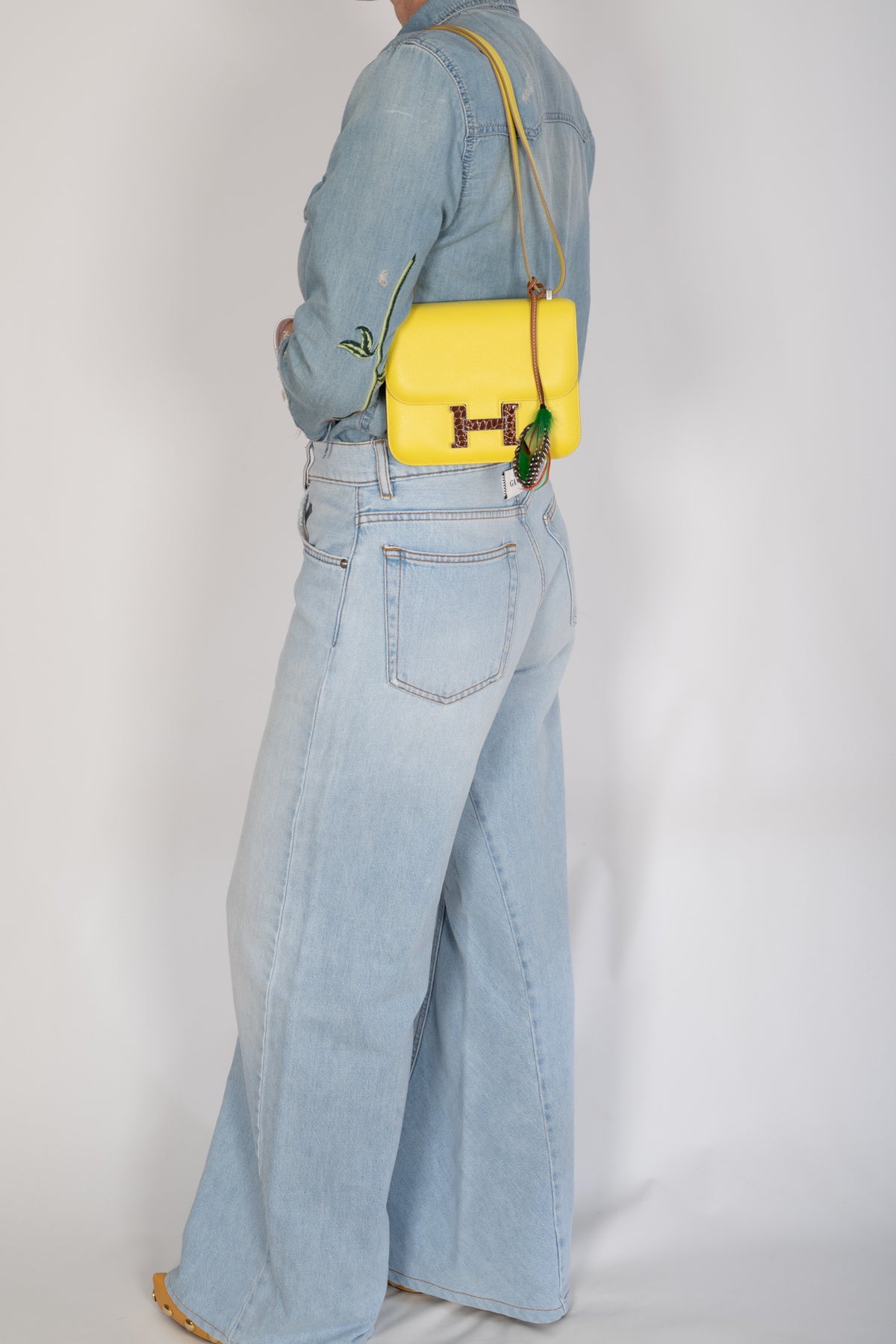 Hermès Constance 18 Mini Lime Evergrain Miel Alligator Buckle Palladium Hardware, worn crossbody by a model, side view, shown with a charm that is not included