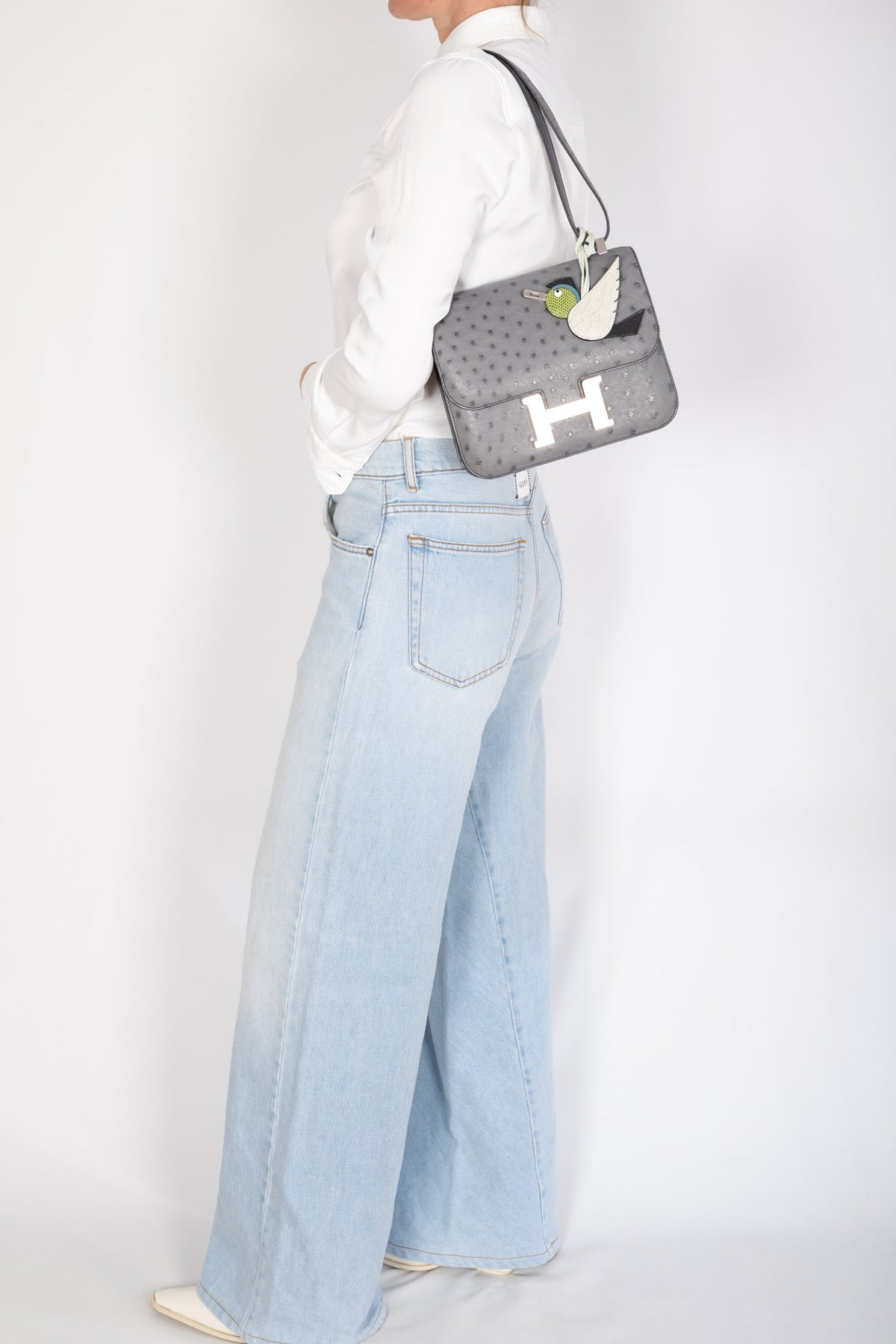 Hermès Constance III 24 Gris Agate Ostrich Palladium Hardware, worn on the shoulder by a model, full-length view, styled with a charm, sold separately