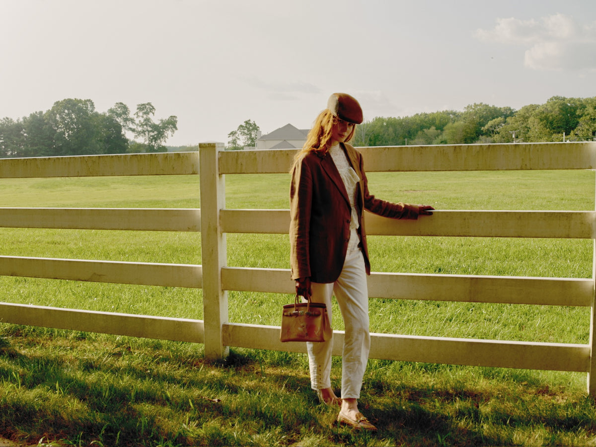 Hermès In and Out Birkin 25 Biscuit Printed Swift Palladium Hardware, carried by a model at a paddock fence, wide view