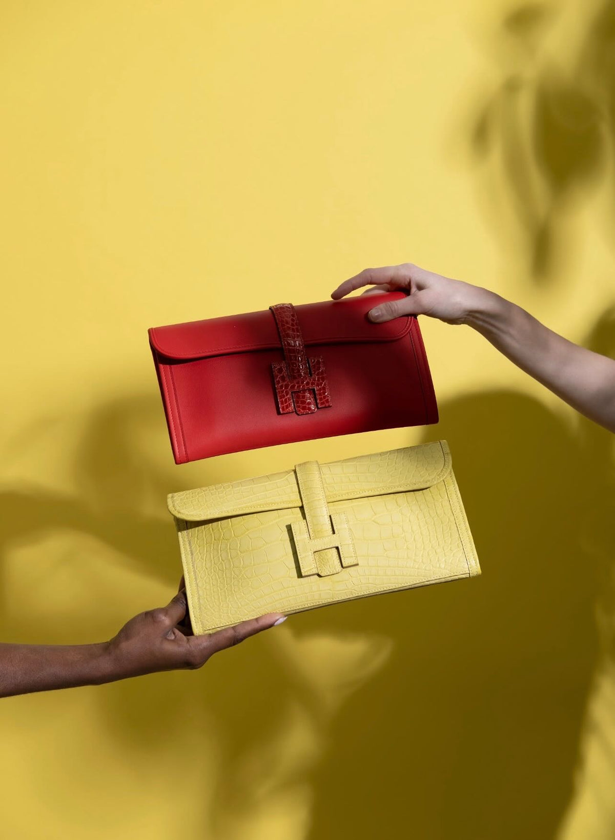 Hermès Jige Élan Rouge de Coeur Shiny Alligator & Swift, held beside a yellow alligator Jige
