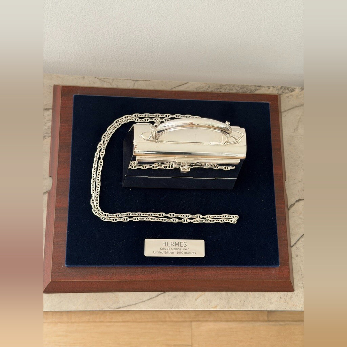 Hermès Kelly 15 Sterling Silver Chaîne d'Ancre Strap, overhead view on the presentation stand with the engraved Hermès plaque