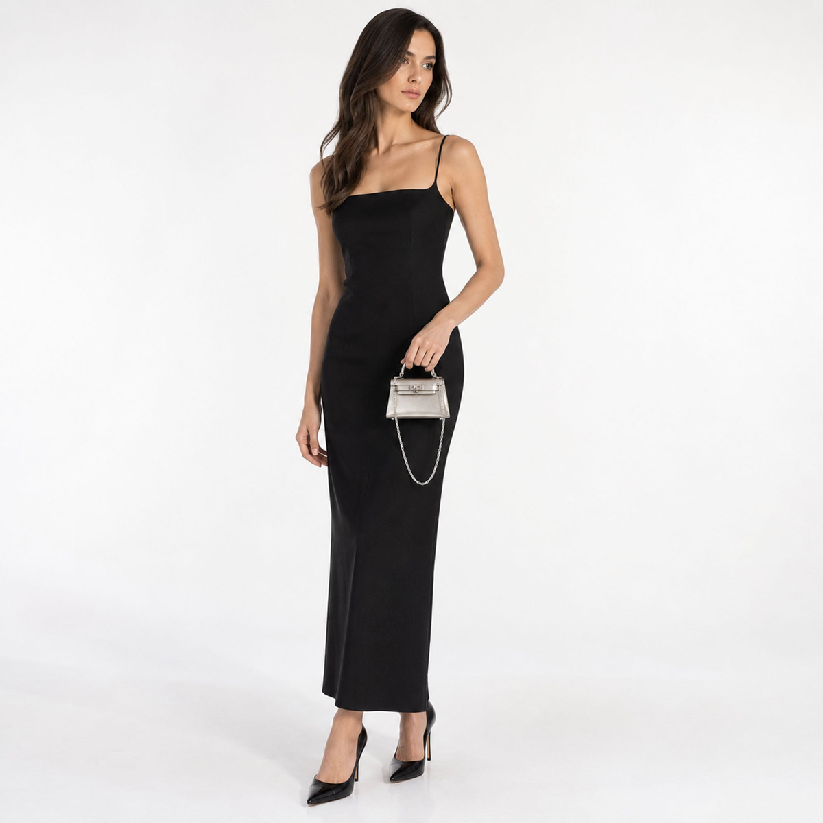 AI-generated styling image of the Hermès Kelly 15 Sterling Silver Chaîne d'Ancre Strap, held by a model in a black dress on a clean white cyclorama; full-length view.