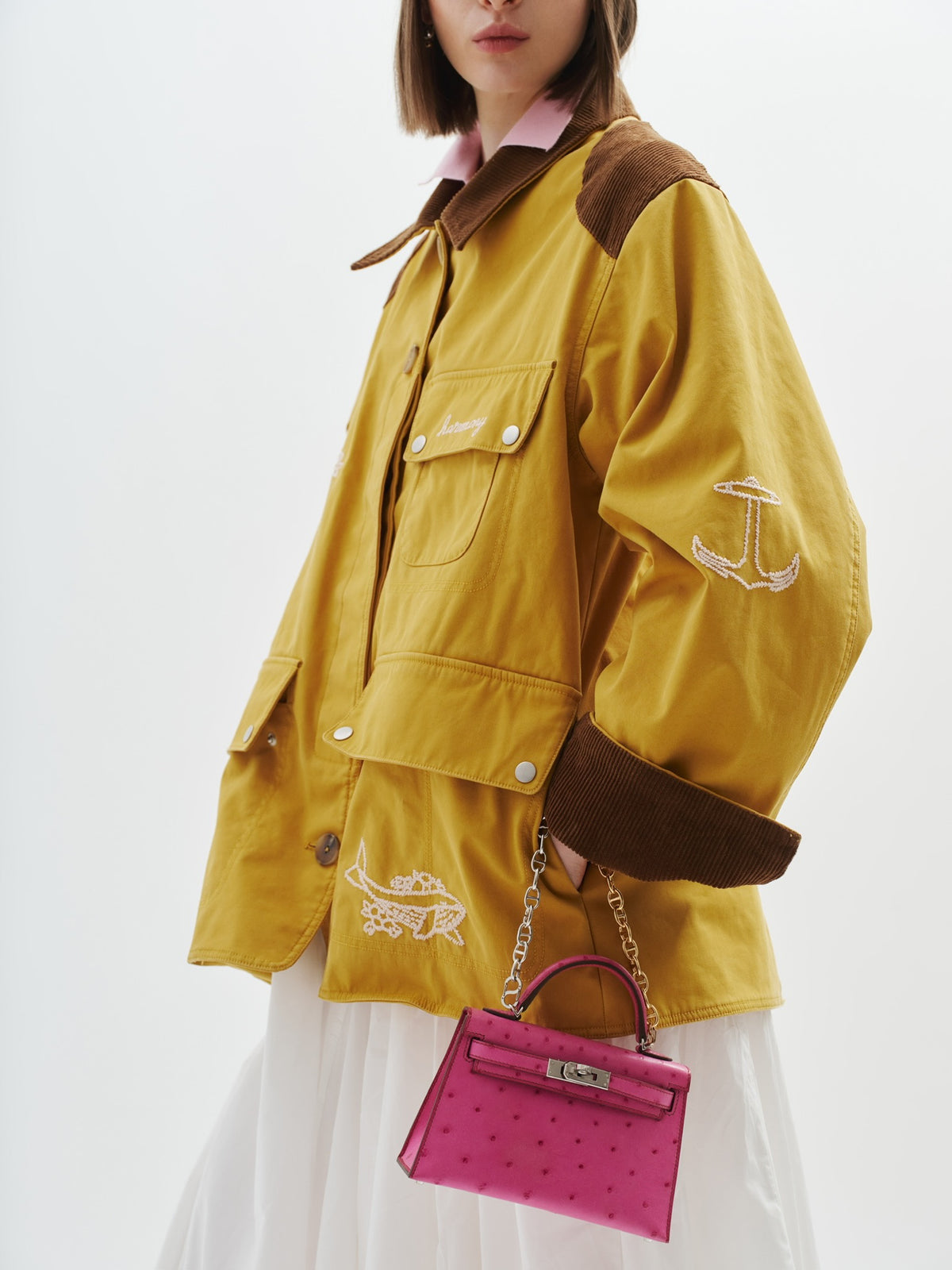 Hermès Kelly 20 Mini II Sellier Rose Tyrien Ostrich Palladium Hardware, carried on a chain by a model, side view