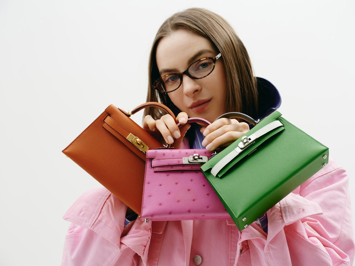 Hermès Kelly 20 Mini II Sellier Rose Tyrien Ostrich Palladium Hardware, held by a model with two other Kelly Mini bags, close view, sold separately