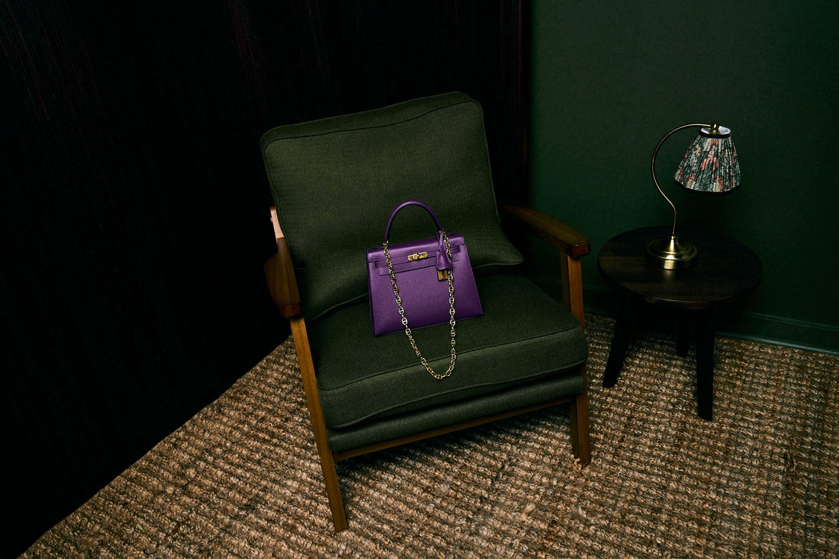Hermès Kelly 25 Sellier Anemone Epsom Gold Hardware, resting on an armchair, wide view
