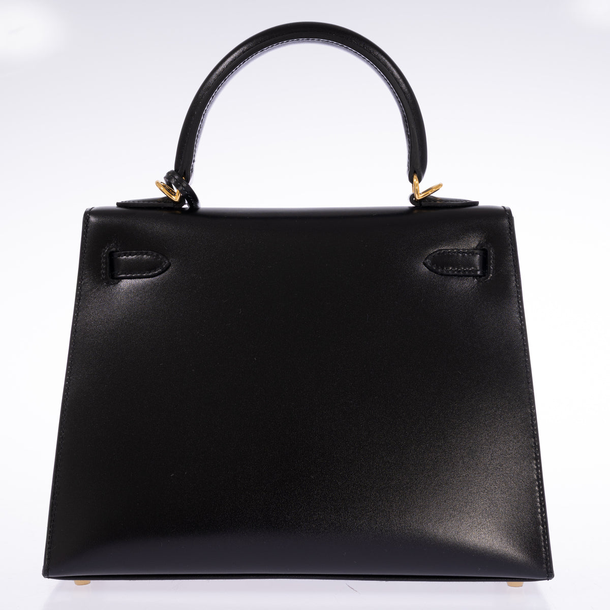 Hermès Kelly 25 Sellier in Noir Box calf with gold hardware, back view showing the handle and the two strap tabs.