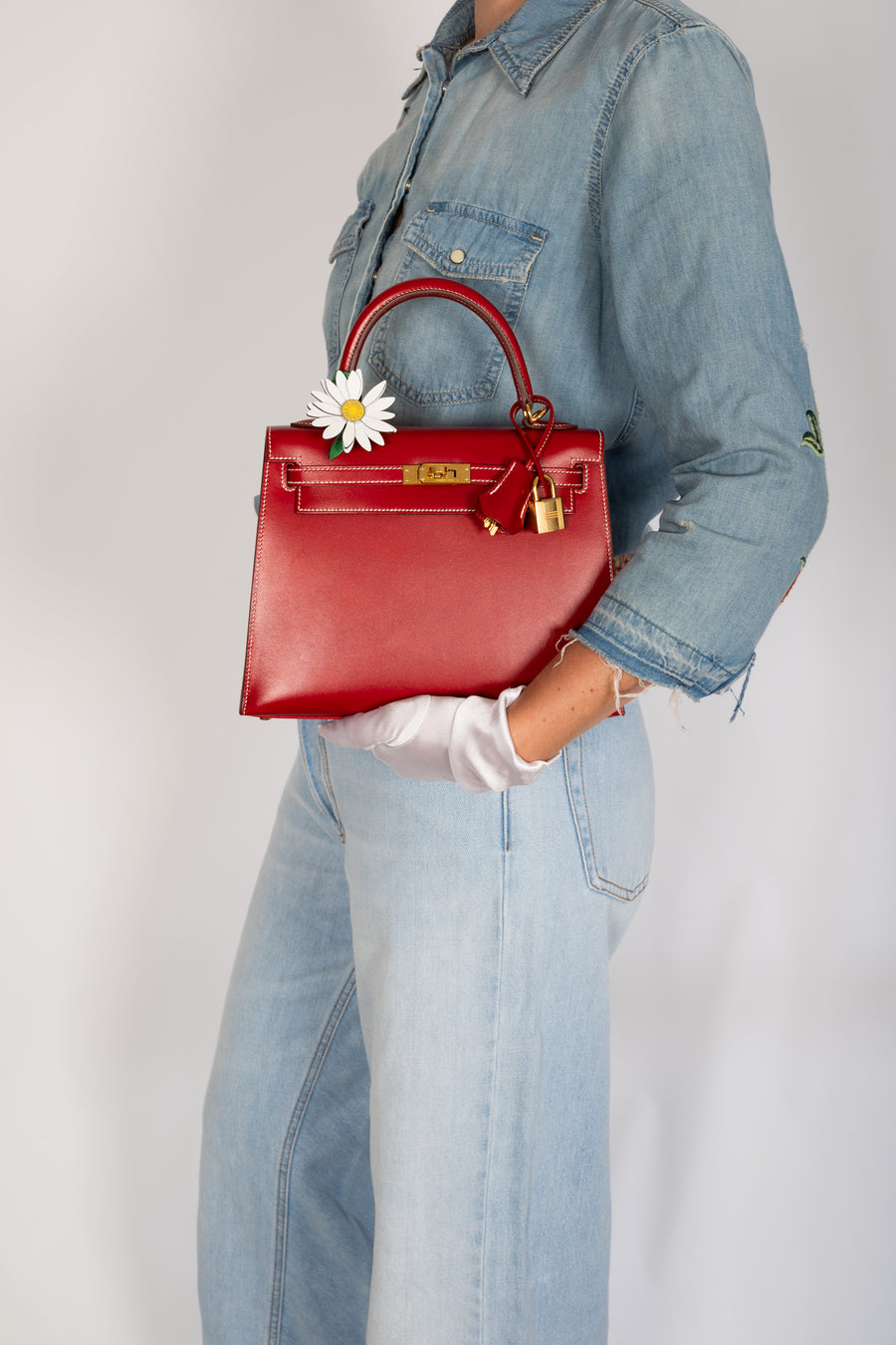 Hermès Kelly 25 Sellier Rouge Piment Box Calf Gold Hardware, carried by the top handle, styled with the Hermès Marguerite Daisy Charm, sold separately