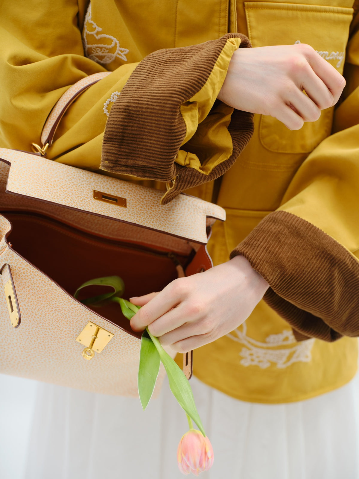 Hermès Kelly 28 Retourne Orange Dalmatian Buffalo Skipper Gold Hardware, held open by a model, interior view with a tulip