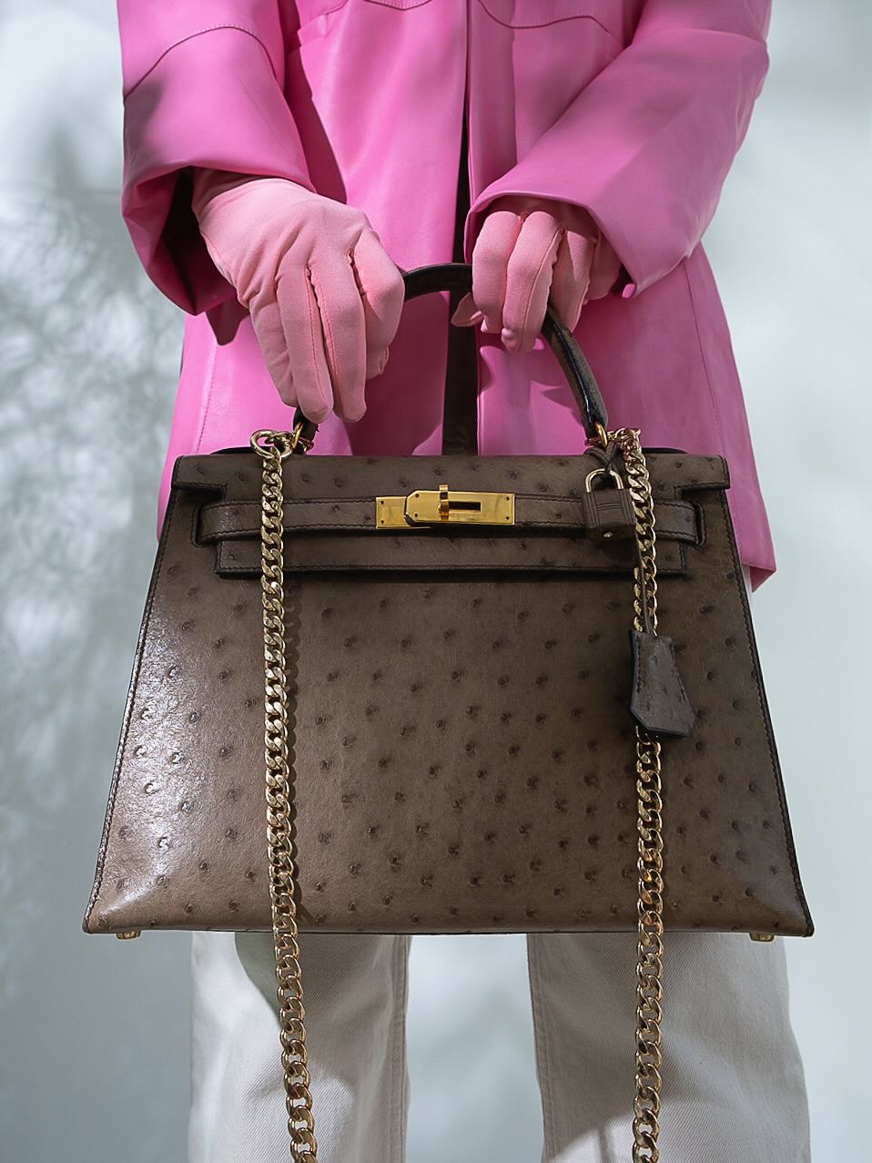 Hermès Kelly 28 Sellier Mousse Ostrich Gold Hardware - Circle W, carried by the handle by a gloved model, with a chain strap