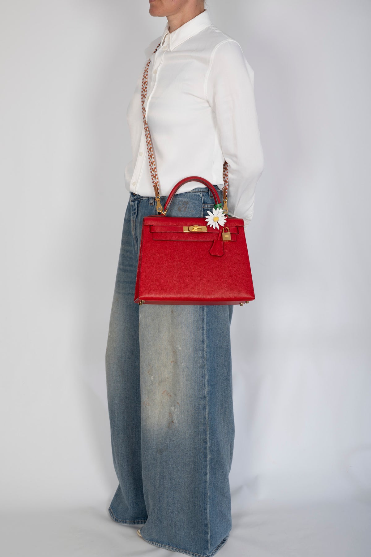 Hermès Kelly 28 Sellier Rouge Casaque Epsom Gold Hardware, worn crossbody by a model with a marguerite charm, charm sold separately