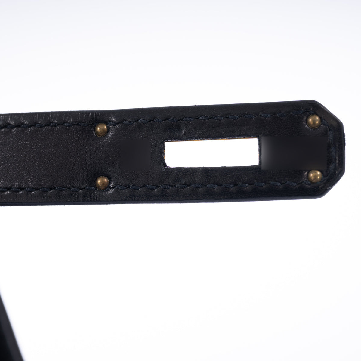 Hermès Kelly 32 Noir Box leather and pony skin with Gold hardware, close view of the underside of a closure strap and its stitching.